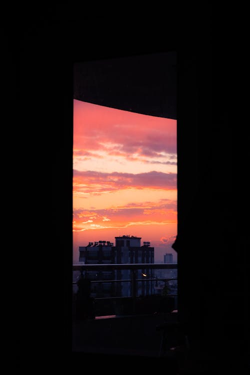 Building behind Window in Room Darkness at Sunset