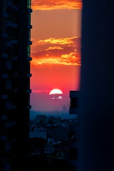 A captivating sunset with orange and red hues framed by city buildings, creating a stunning urban skyline.