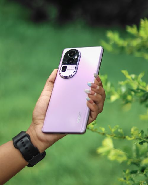 Free A hand holding a purple smartphone against a green outdoor background. Stock Photo