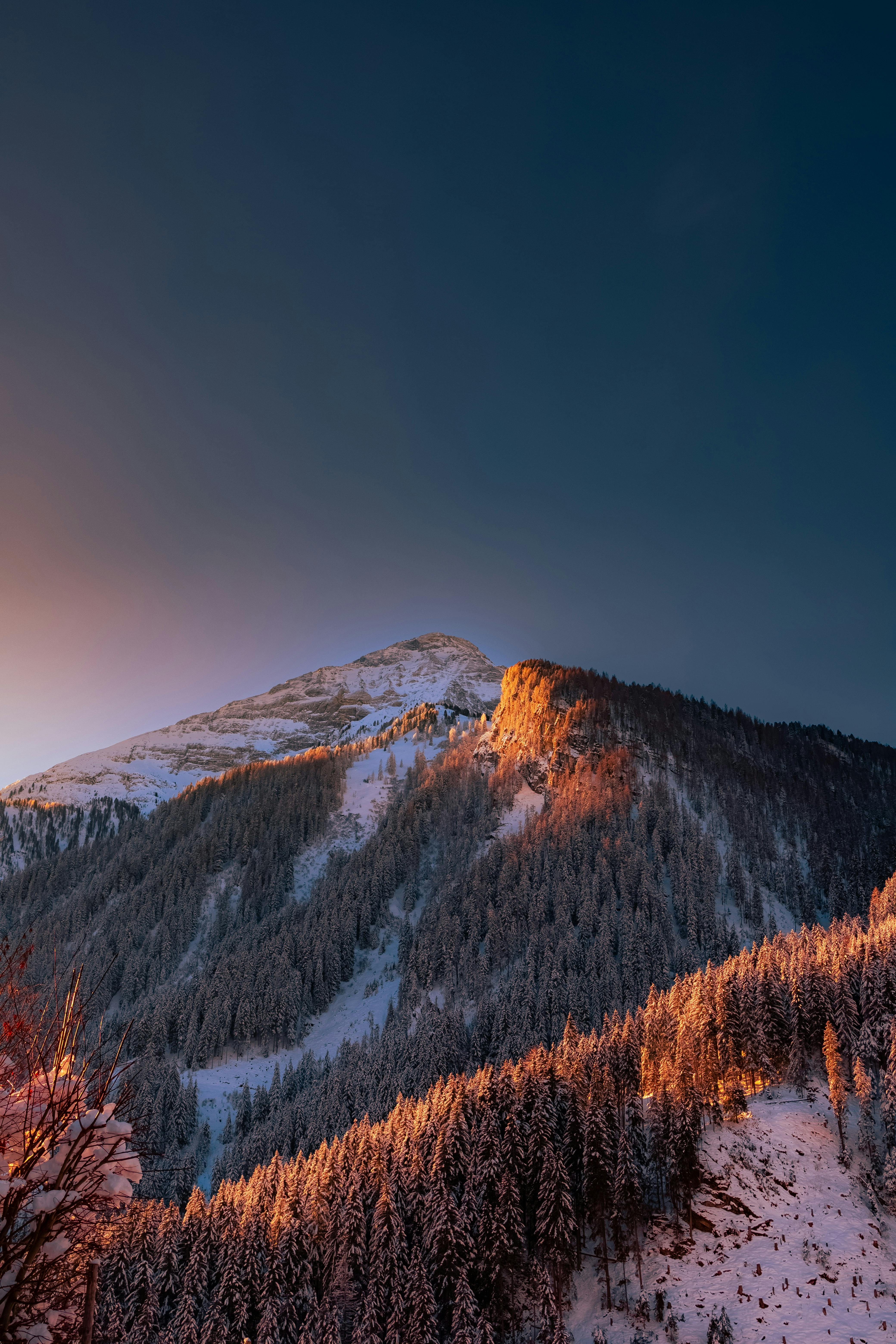 A stunning winter evening view of snow-covered mountains in Zillertal, Austria, with a vivid sunset sky.