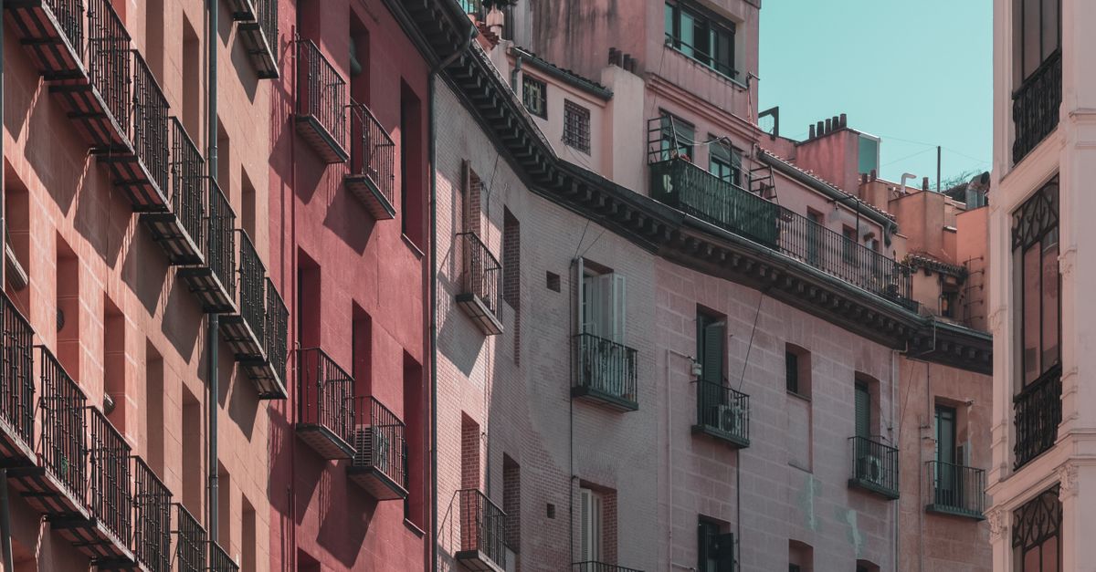 Iconos de casa y porcentaje de impuestos superpuestos, simbolizando el aumento del IVA en viviendas turísticas.