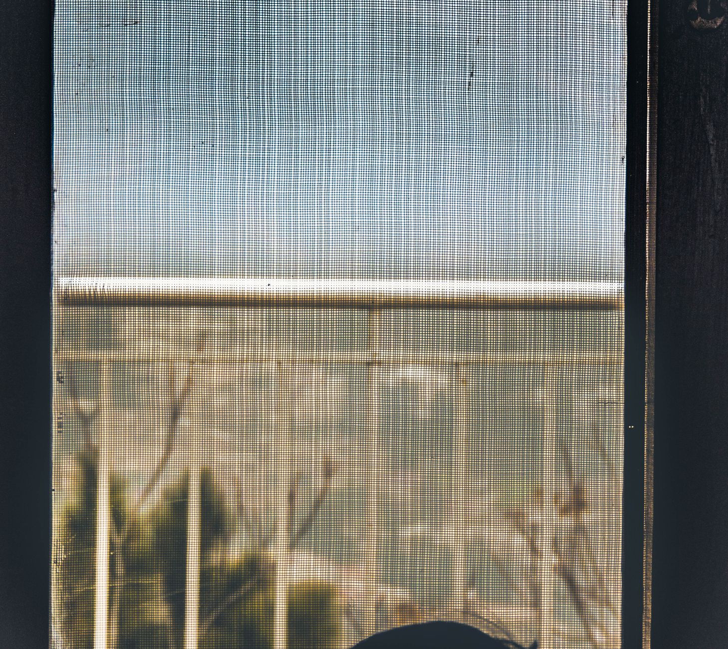 A minimalist view through a mesh screen showing railings outdoors.