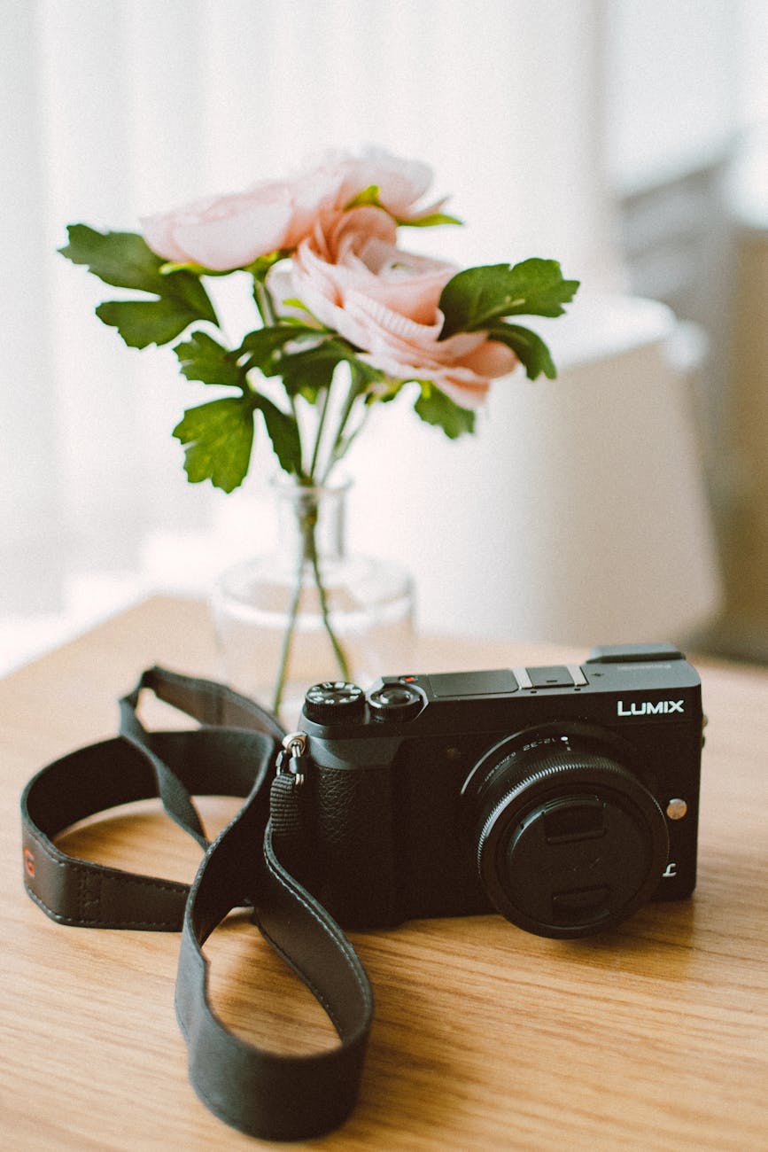 A camera and rose bouquet placed elegantly on a wooden table indoors.