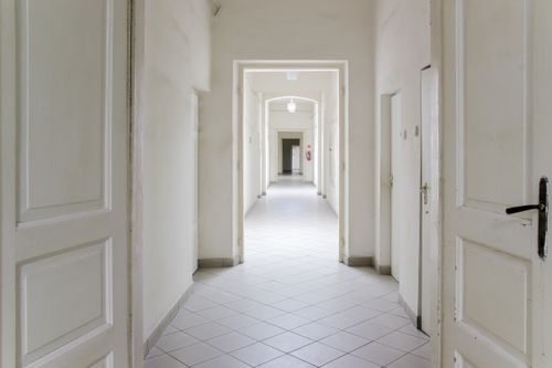 Free A long, white empty corridor with open doors, ideal for design concepts. Stock Photo