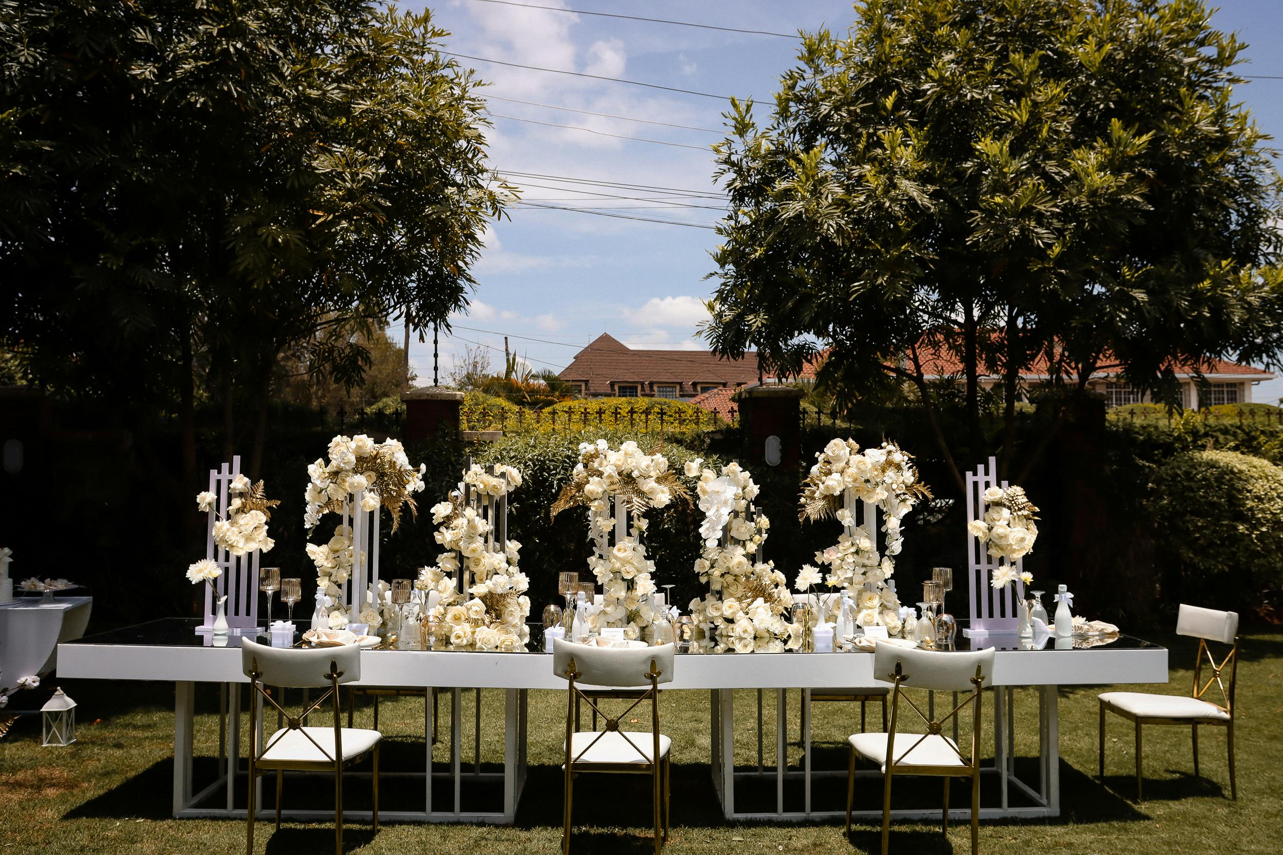 An elegant garden party setup with floral arrangements and chairs under sunlight.