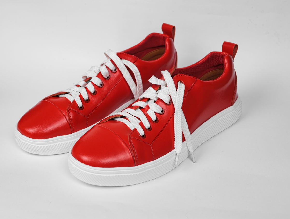 A pair of unbranded red leather low-top sneakers with white laces — photo by Ahimsa - OM on Pexels
