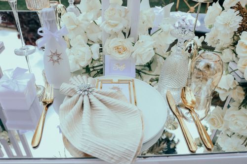 Free A beautifully arranged outdoor table setting featuring white roses, fine glassware, and gold cutlery. Stock Photo