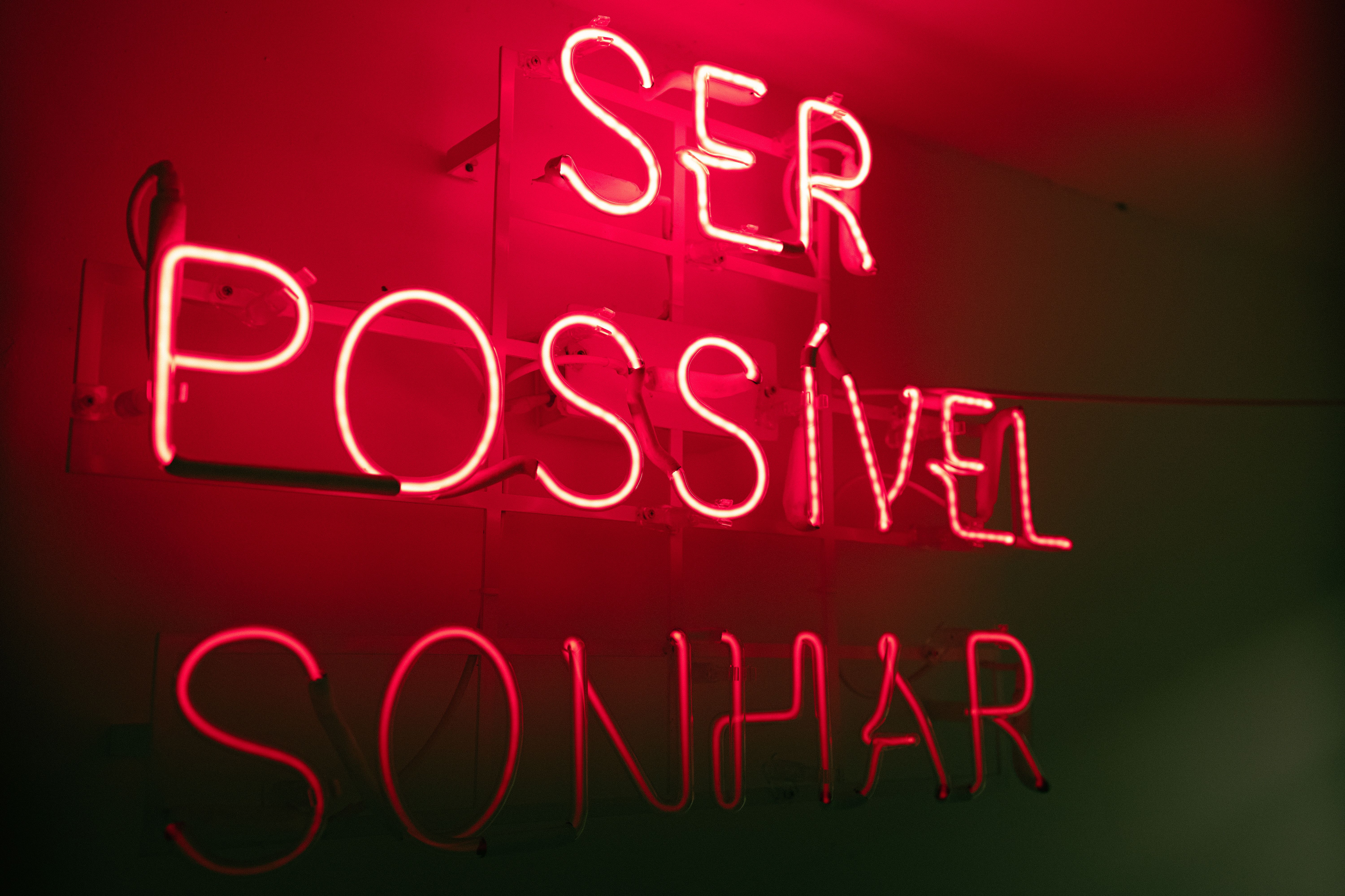 Red neon sign displaying Portuguese words in a modern setting.