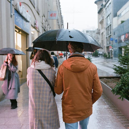 Woman and Man with Umbrella Walking on Street in City
