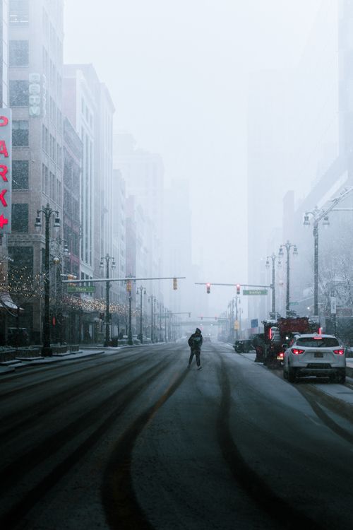 Free A lone person walks through a snowy, urban street in Detroit. The city is under a cold winter snowstorm. Stock Photo