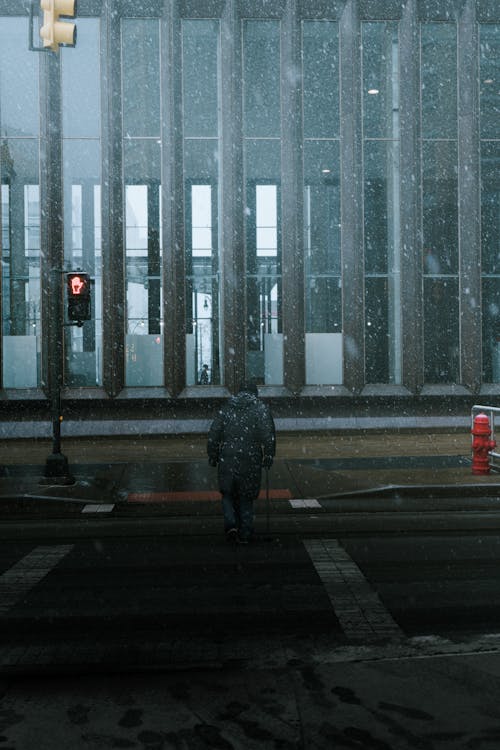 A man walking across a street in the rain
