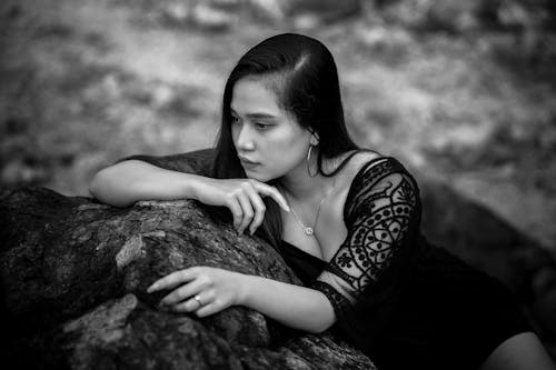 A woman in black and white sitting on a rock
