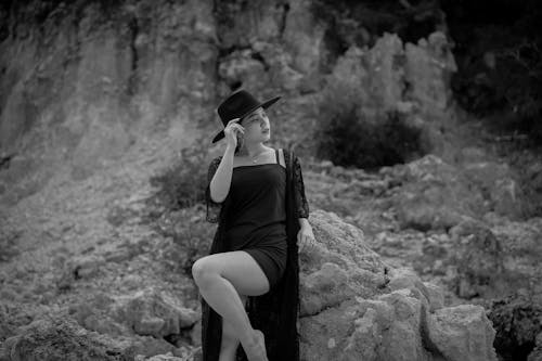 Woman in Hat and Dress Standing by Rock