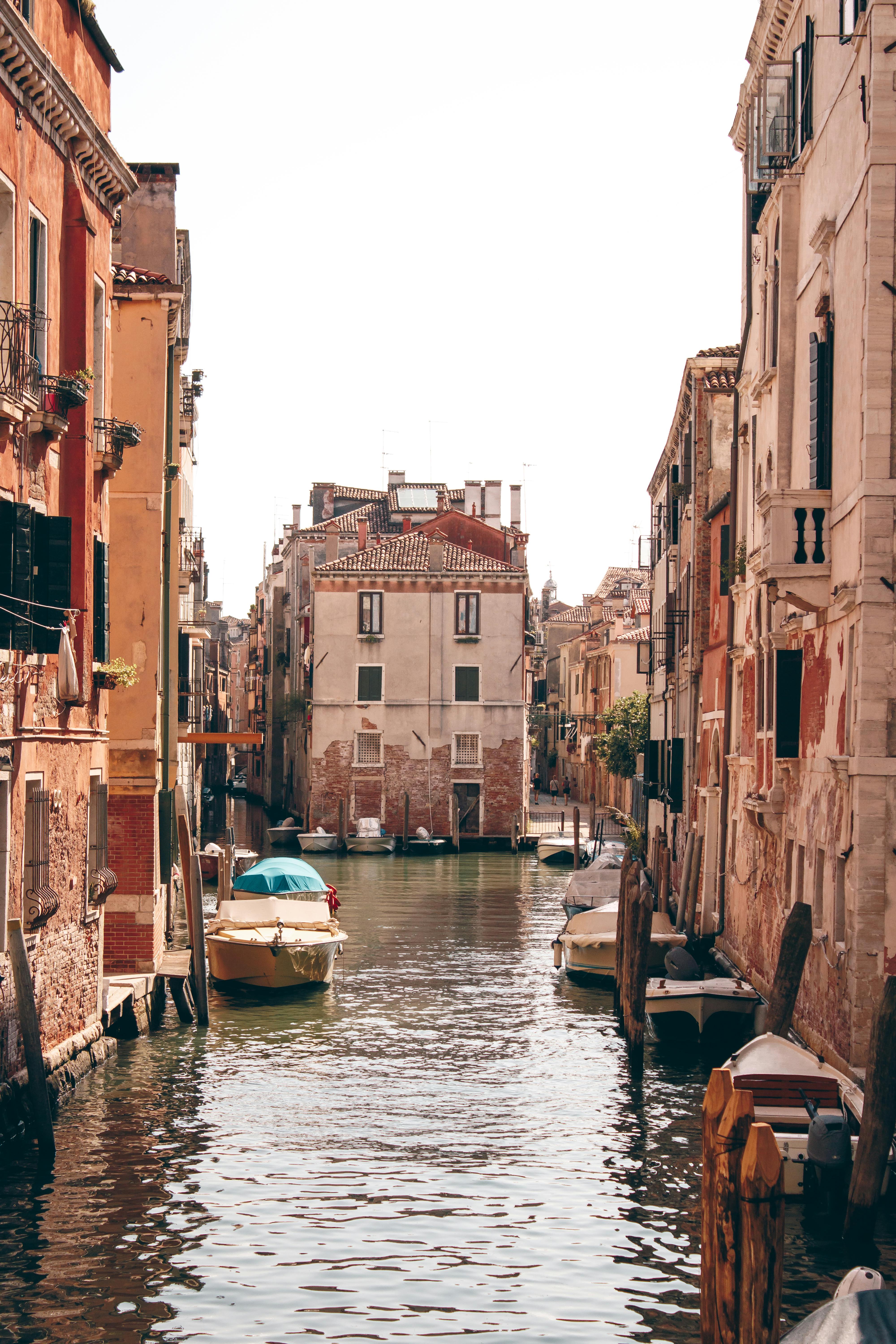 Serene view of a canal in Venice, Italy, with boats and historical buildings under summer sun.