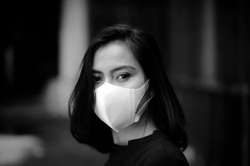 Free Black and white portrait of a woman wearing a face mask looking directly at the camera. Stock Photo