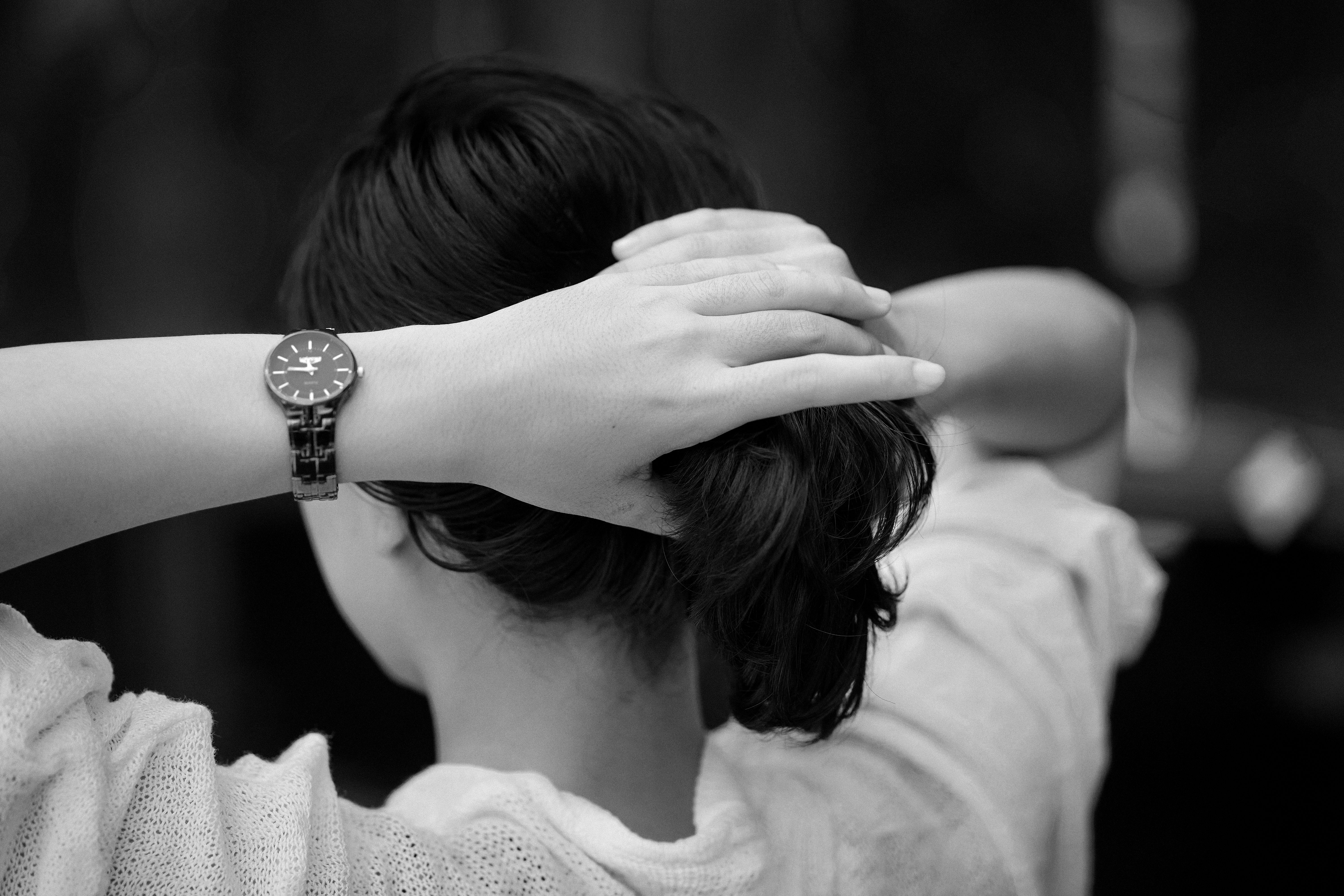 Elegant monochrome photo of a woman adjusting her hair, focus on watch.