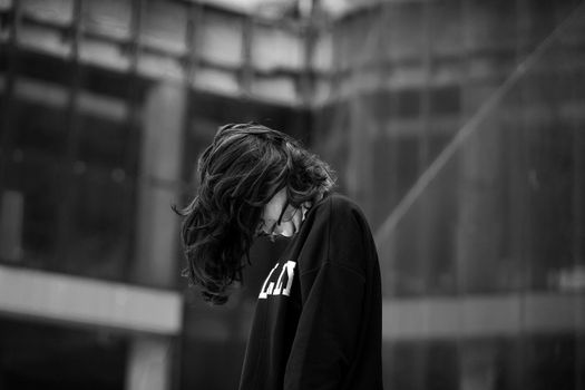 A woman stands in solitude, captured in a moody black and white urban portrait.