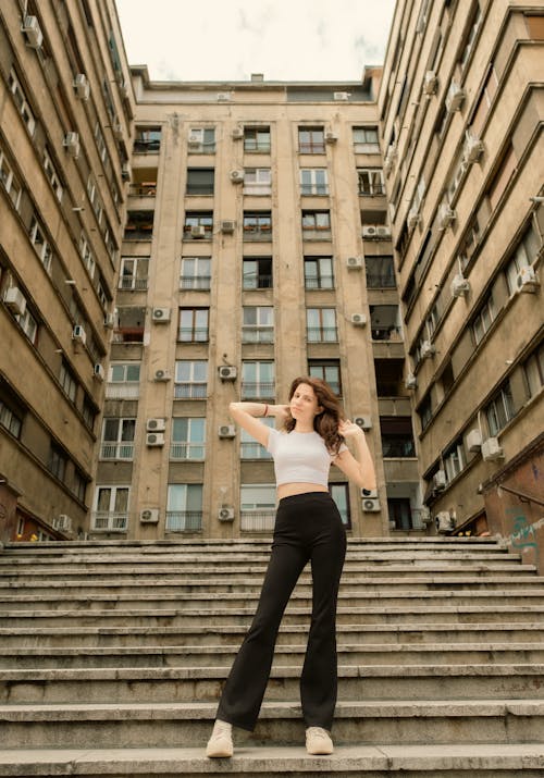 Young Woman in White Top Posing Against Old Apartment Building
