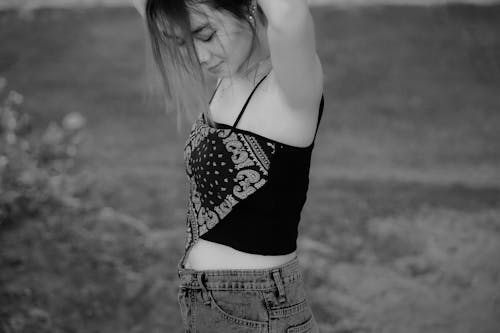 Black and White Photo of a Young Woman in a Tank Top Standing Outside 