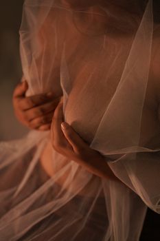 A close-up artistic portrait of a woman embracing herself under a sheer veil, creating a mysterious and intimate mood.