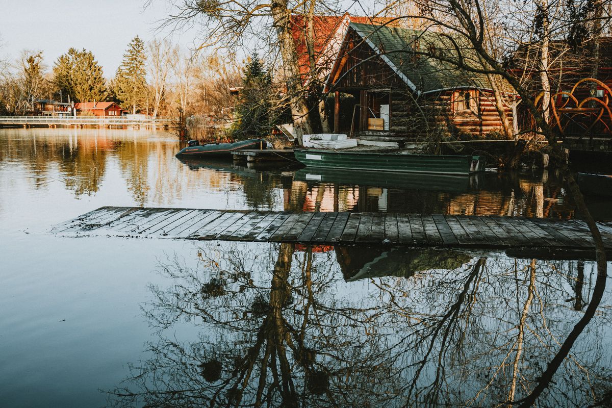 Rustic lakeside cabins and boats reflected in calm water