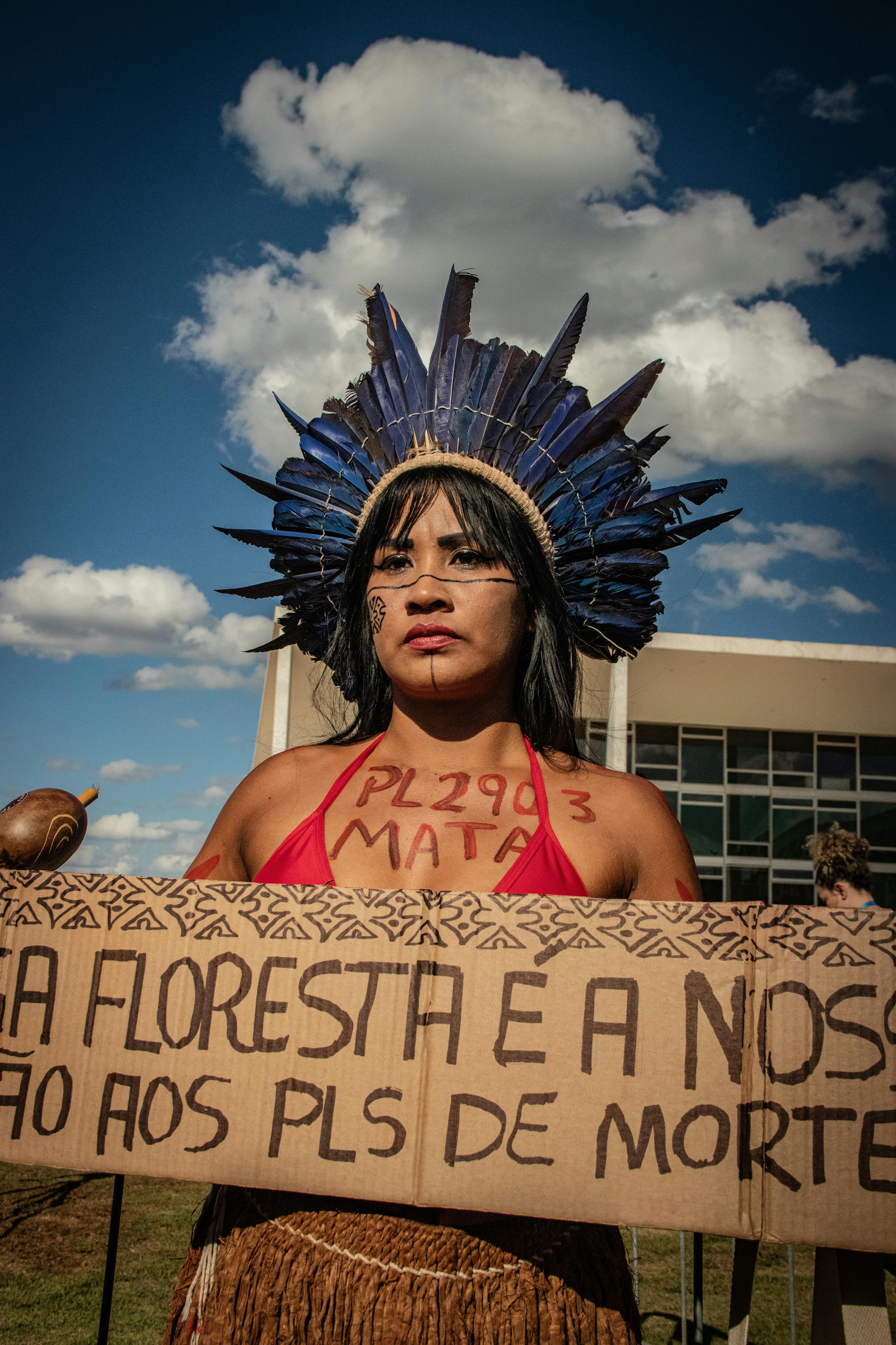 young woman wearing a plume holding a sign