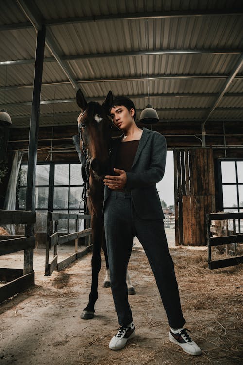 A man is standing next to a horse in a barn