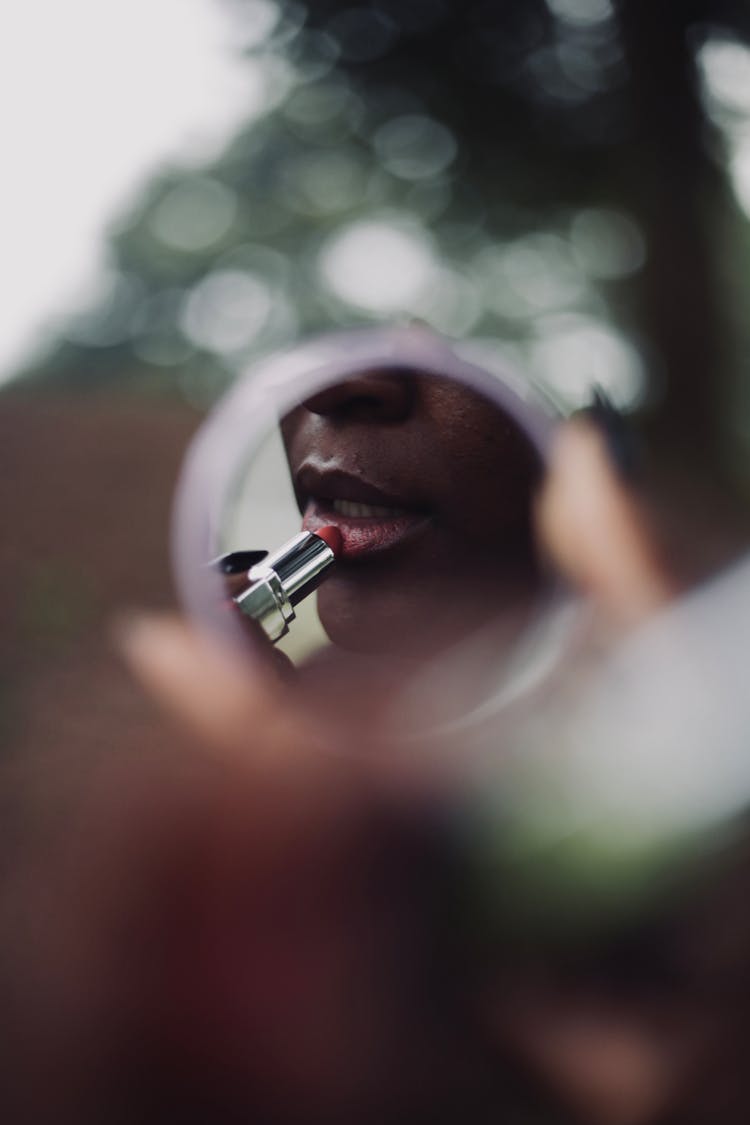 Reflection Of Woman Applying Lipstick