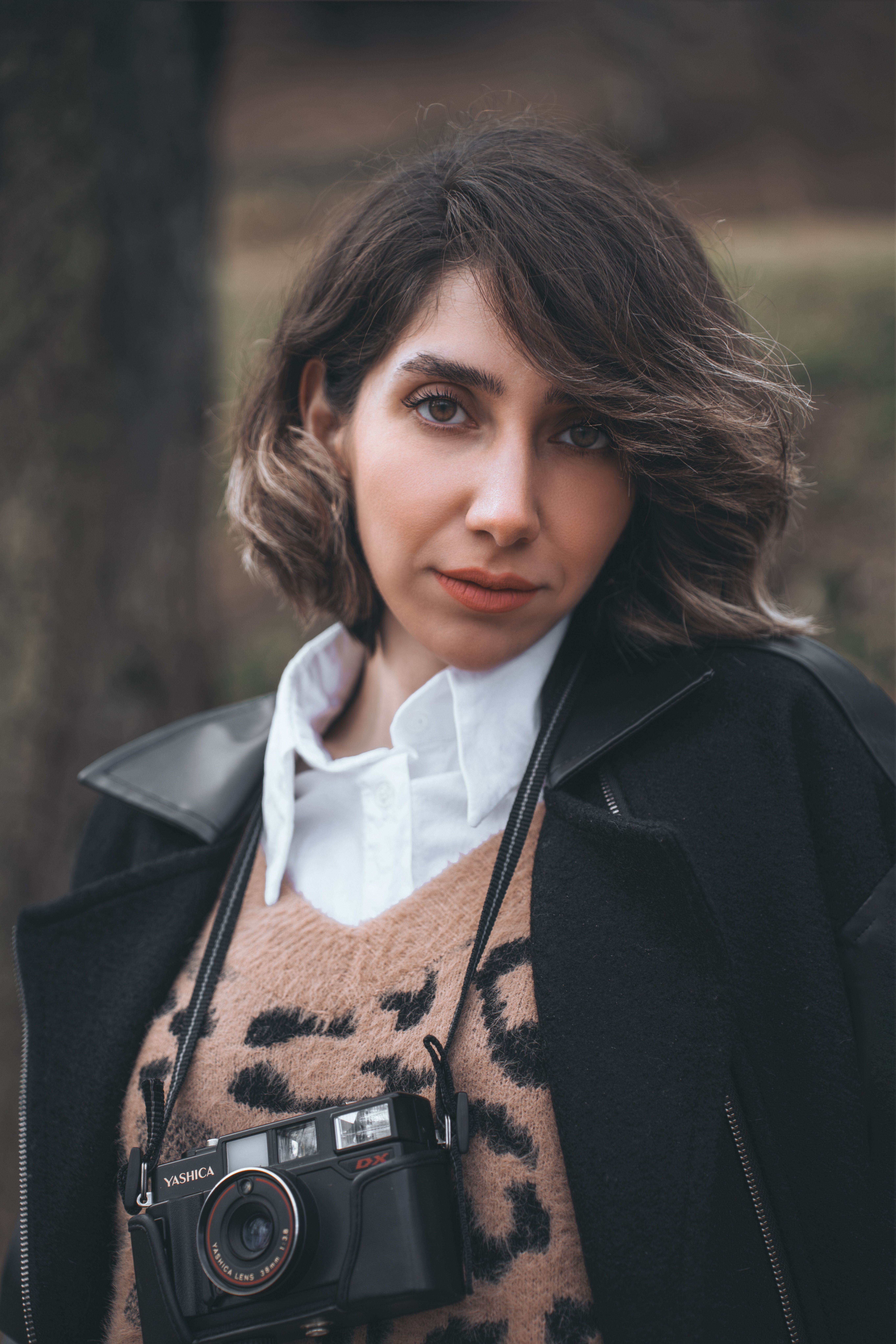Stylish portrait of a woman with a vintage camera, showcasing winter fashion.