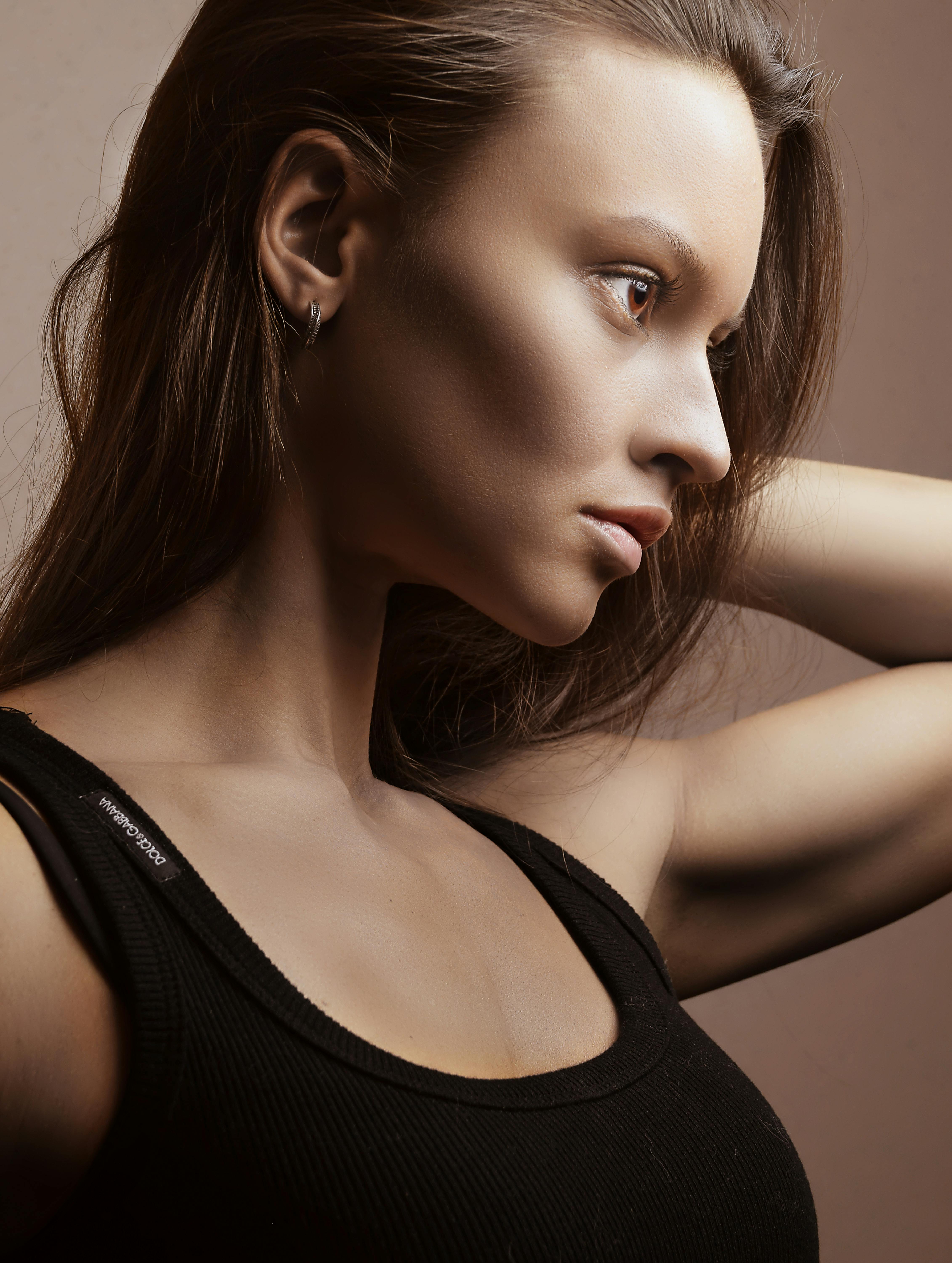Elegant profile portrait of a woman fixing her hair, showcasing graceful femininity.