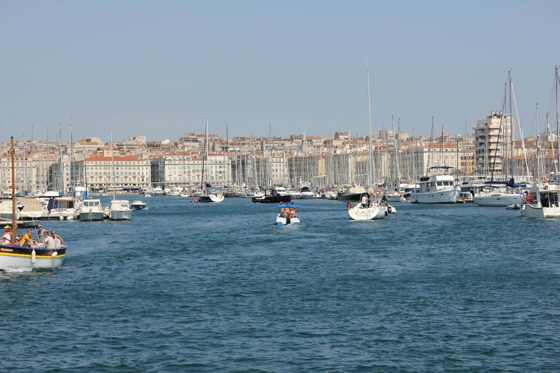 Explore the bustling harbor of Marseille with boats against a backdrop of historic architecture.