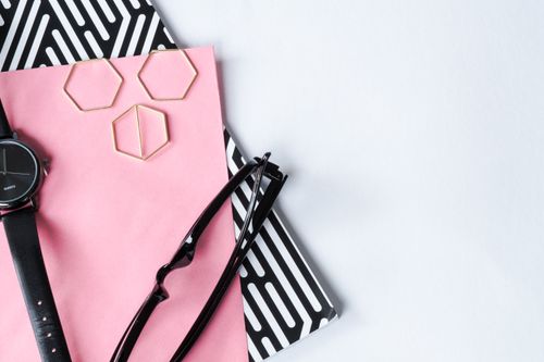 Free Stylish flat lay featuring a watch, glasses, and geometric shapes on a pink and black background. Stock Photo