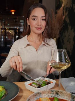 Woman dining elegantly in a restaurant, enjoying a gourmet meal with white wine.