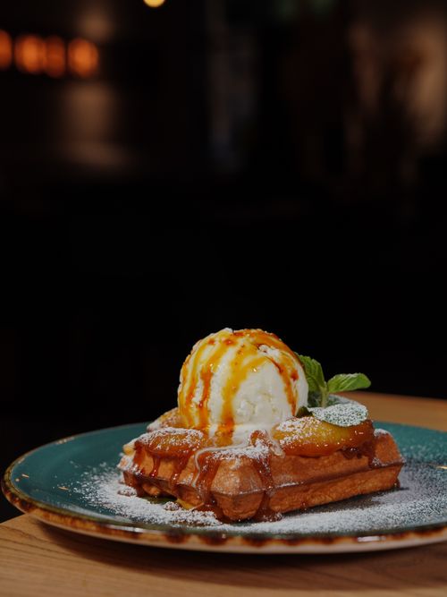 Free Appetizing waffles topped with ice cream and caramel sauce served on a stylish plate. Stock Photo