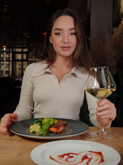 Woman Sitting by Table with Meal and Champagne