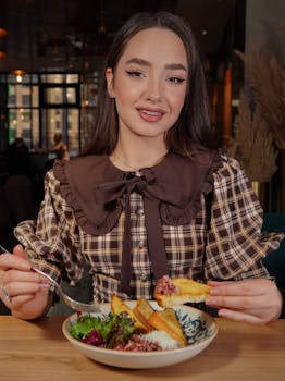 Fashionable woman savoring a healthy meal at a cozy indoor restaurant setting.