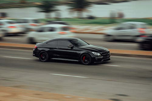 A Black Mercedes-AMG C63 Driving Fast on a Street 