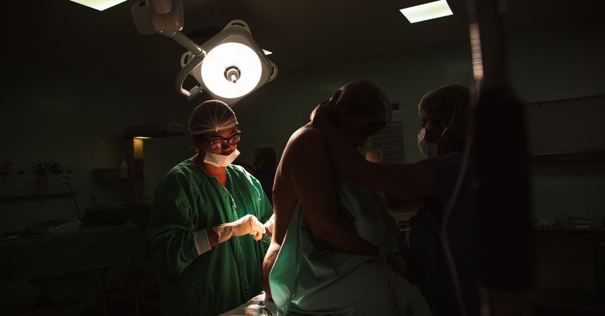 Surgeons and nurses preparing for an operation under bright surgical lights.