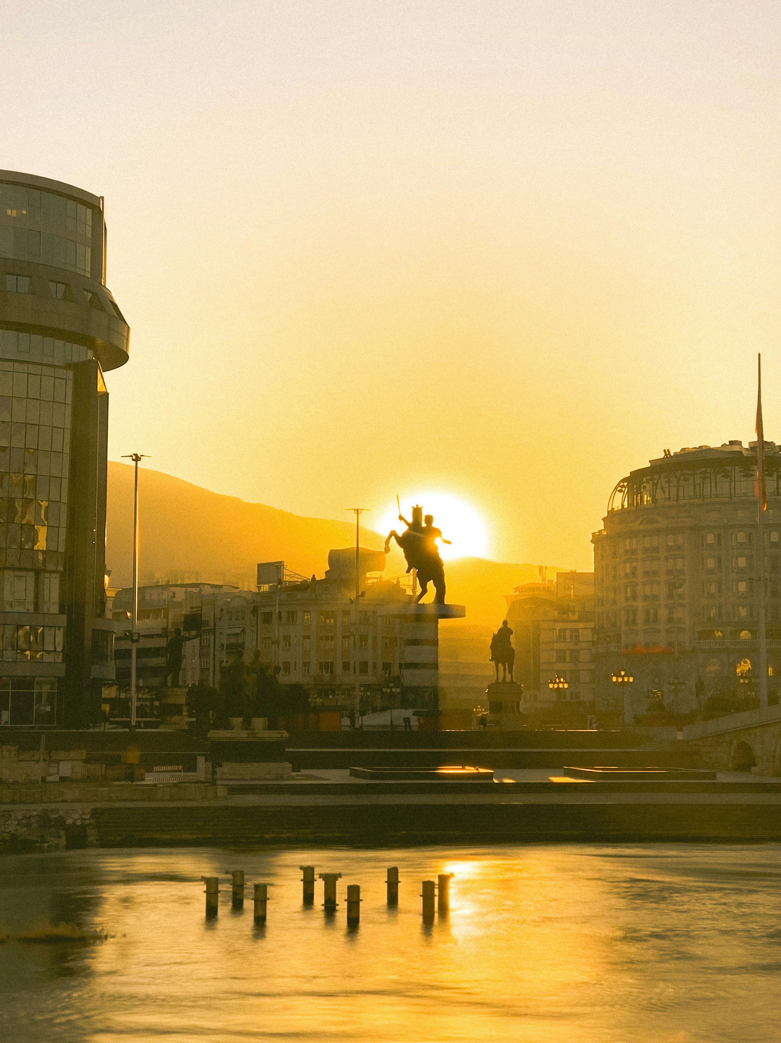 Enchanting sunset over Skopje cityscape featuring the iconic equestrian monument with a warm hue.