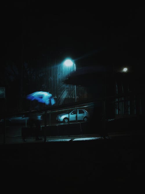 A person with an umbrella walking down the street at night