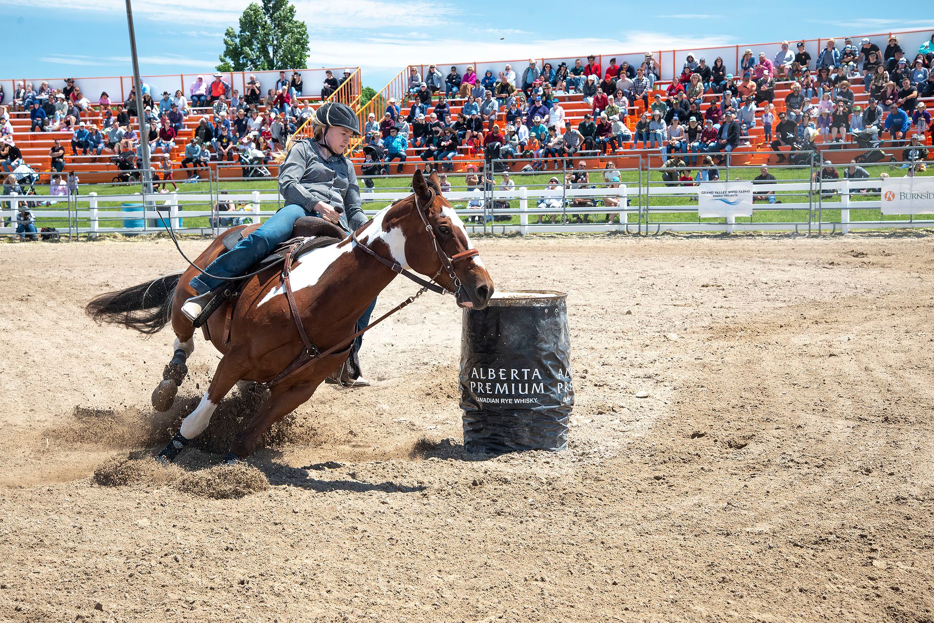 Exciting barrel racing competition with rider maneuvering horse in the arena.