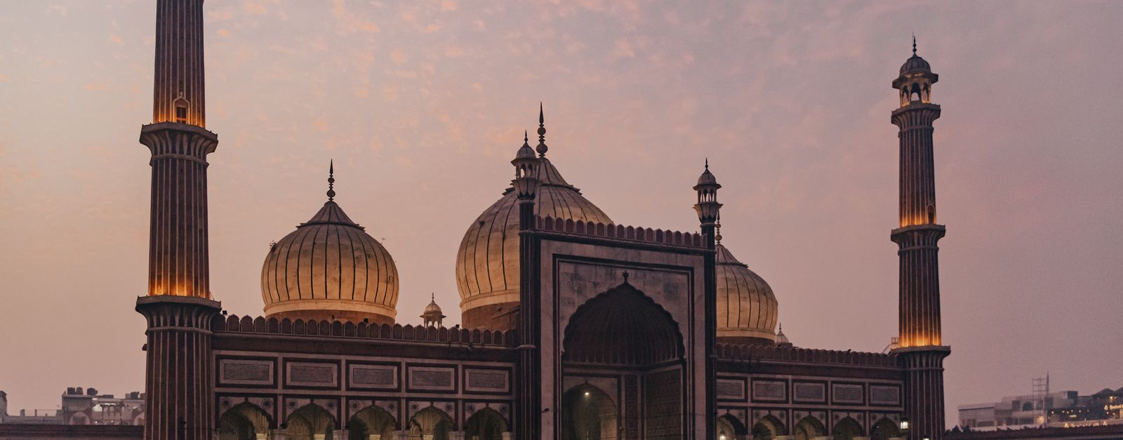 A stunning view of Jama Masjid in Delhi at dusk, showcasing Mughal architecture and vibrant evening sky.
