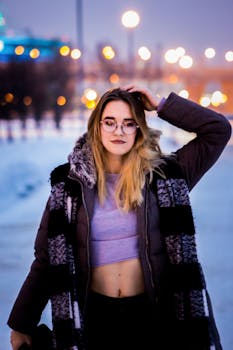 冬夜里，一位戴眼镜的年轻女子穿着时尚服装摆姿势