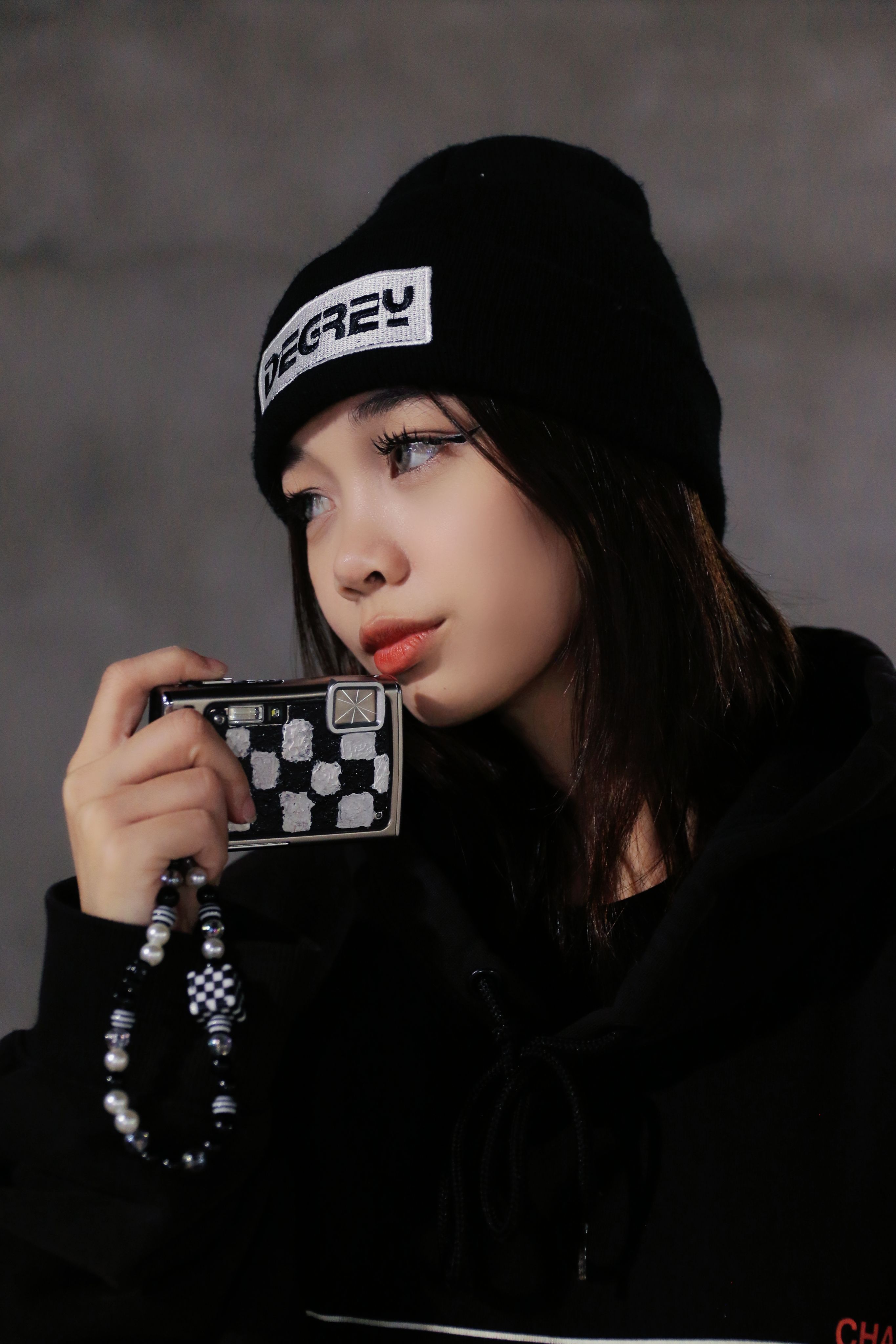 Fashionable young woman in a beanie holding a checkered accessory, showcasing urban style.