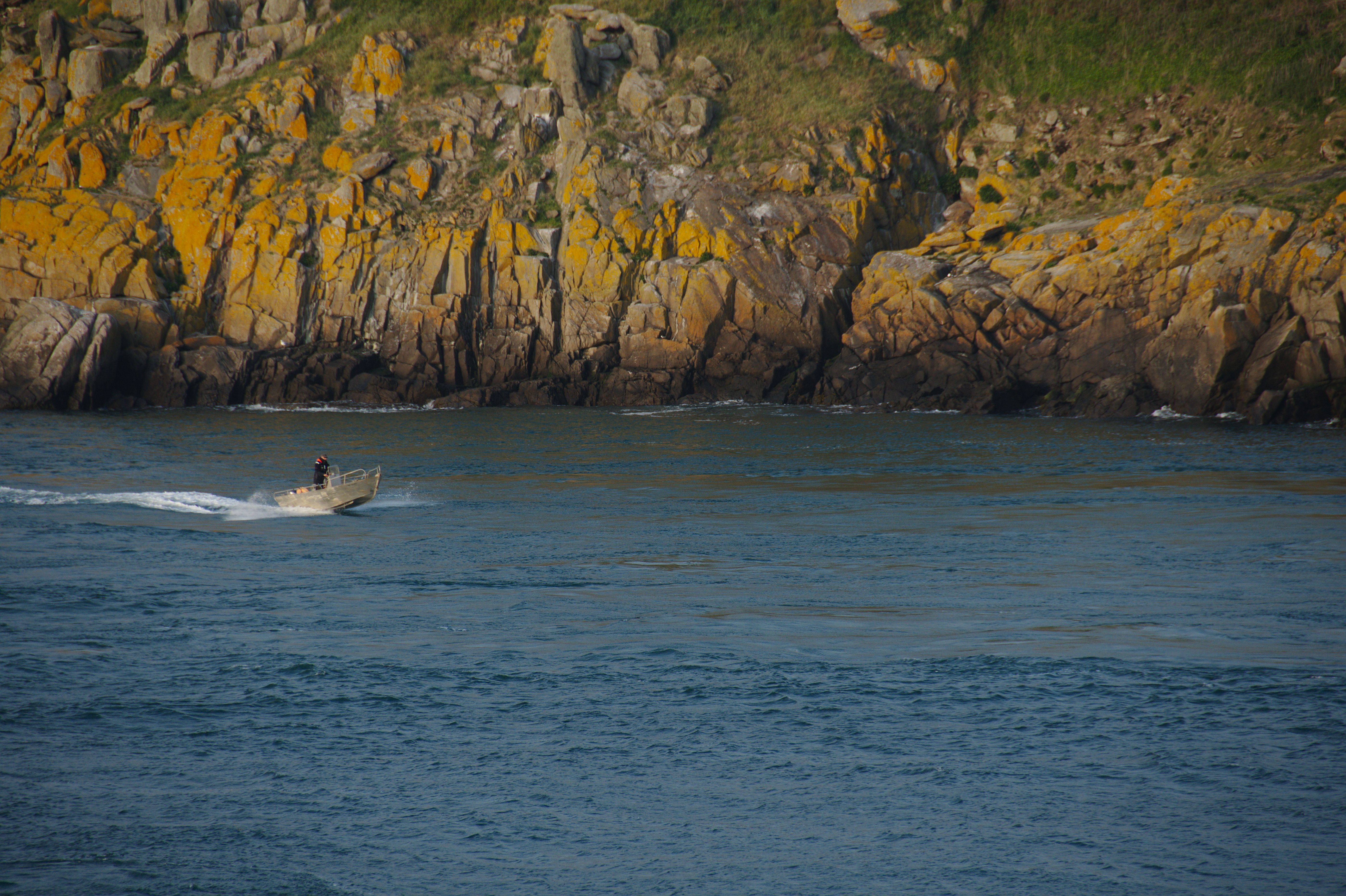 Motorboat Speeding Along a Rocky Cliff · Free Stock Photo