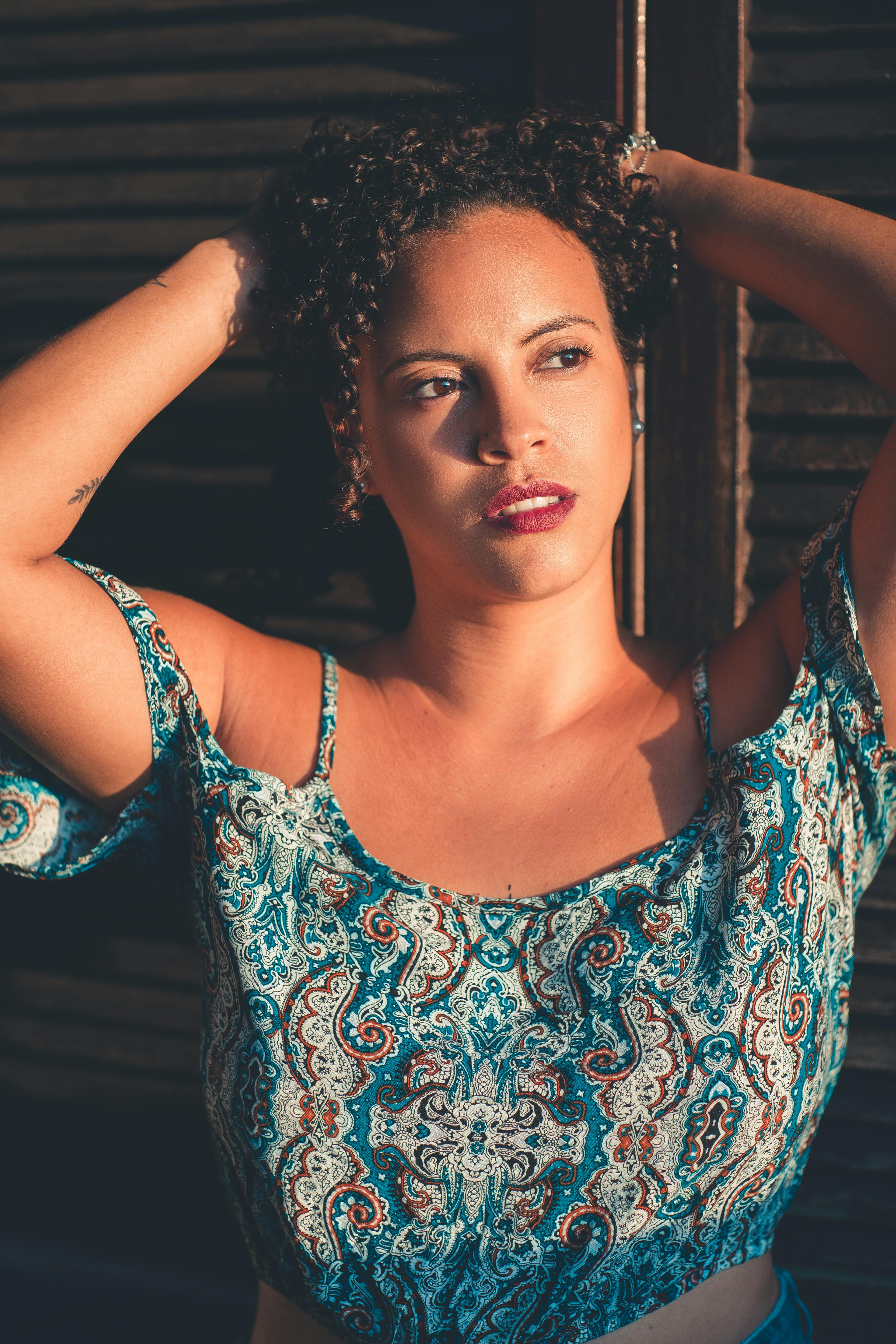 一位卷发红唇的时尚女性穿着露脐上衣在户外摆姿势