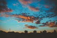 城市天际线映衬在充满活力的日落天空下，云层显得格外戏剧性