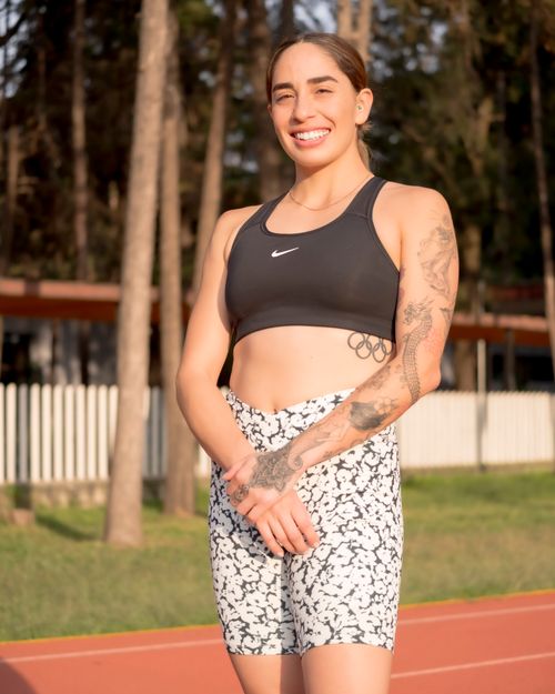 Free Confident female athlete standing on track during sunny day, wearing sportswear. Stock Photo
