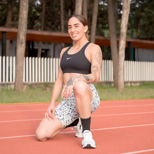 A woman in a sports bra and shorts squatting on a track