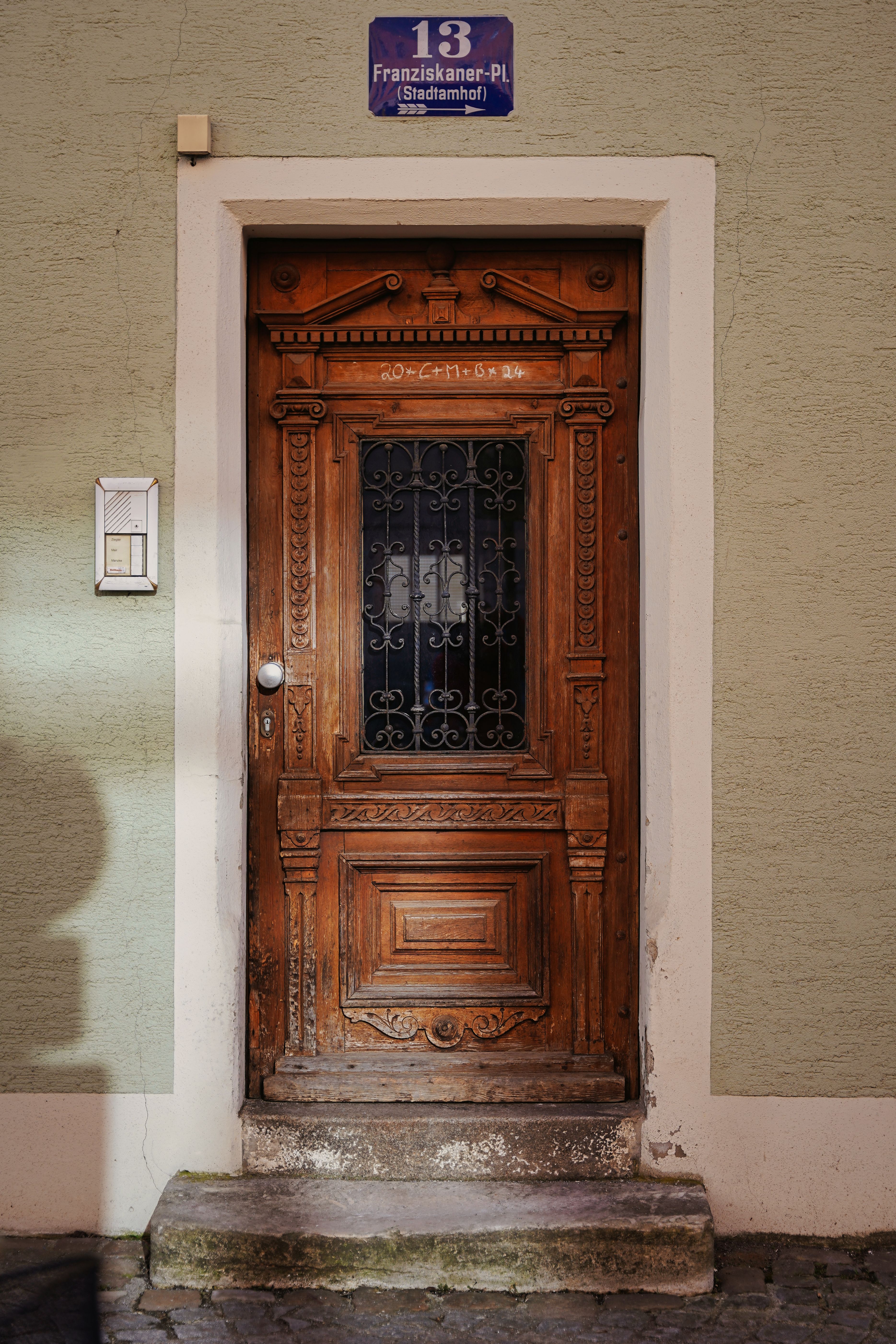 Detailed ornate wooden door on a historic stone facade at Franziskaner-PL, Stadtamhof.